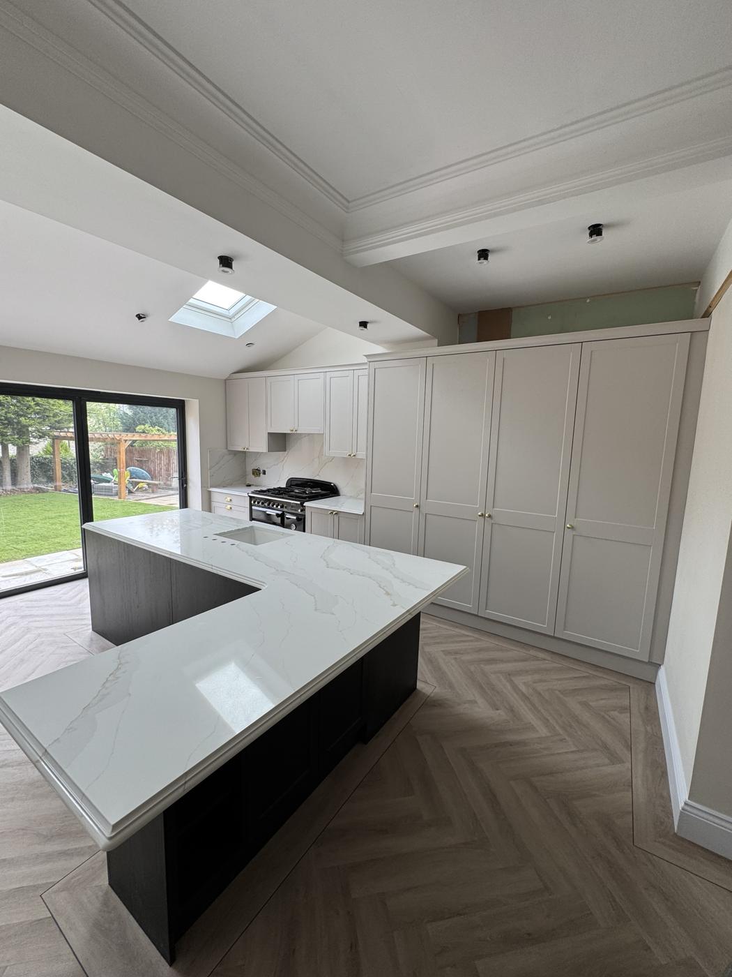 Light grey shaker kitchen extension with tall larder units and a marble-effect island