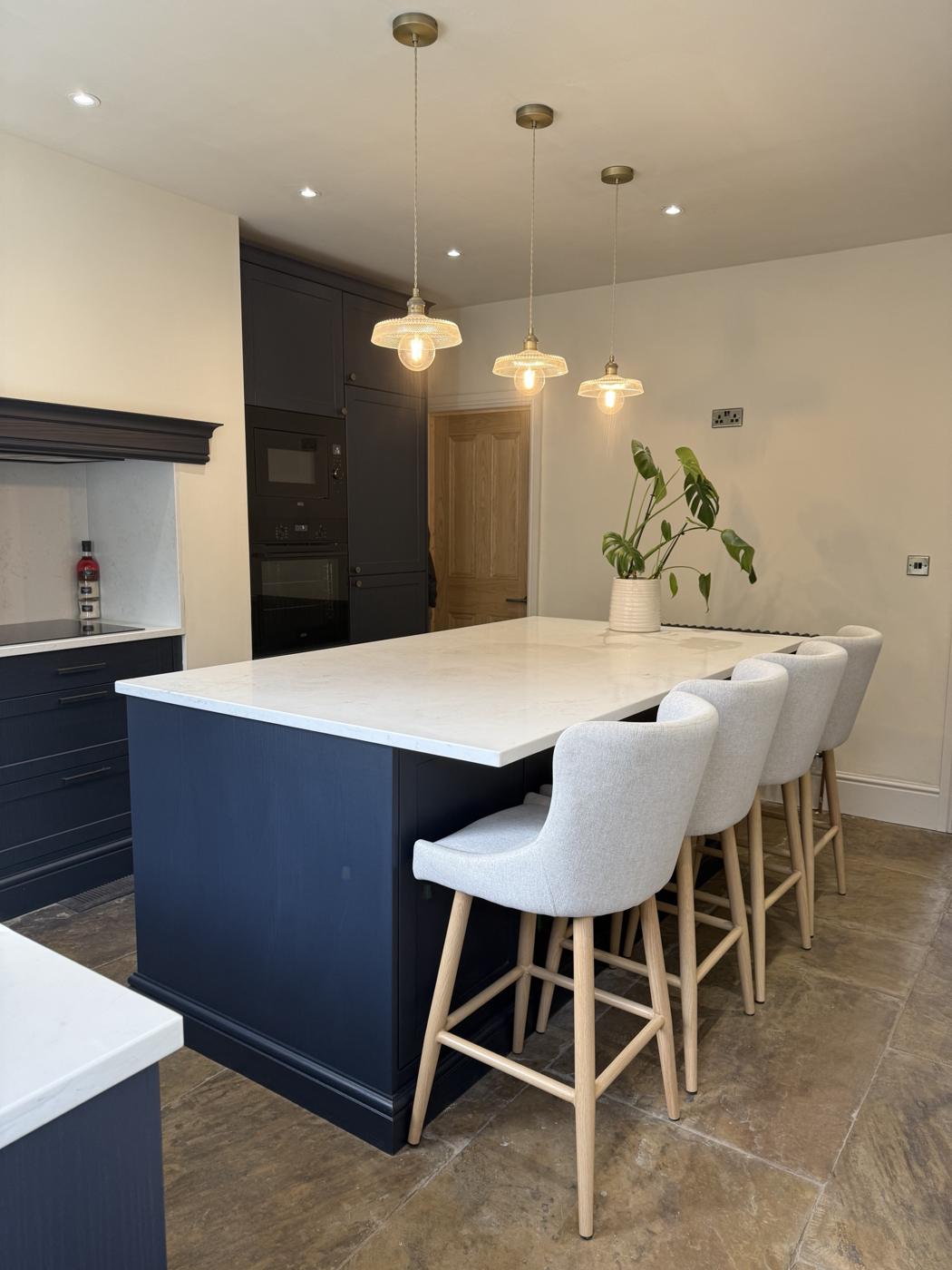 Navy shaker kitchen island with quartz worktop, pendant lights and bar stools